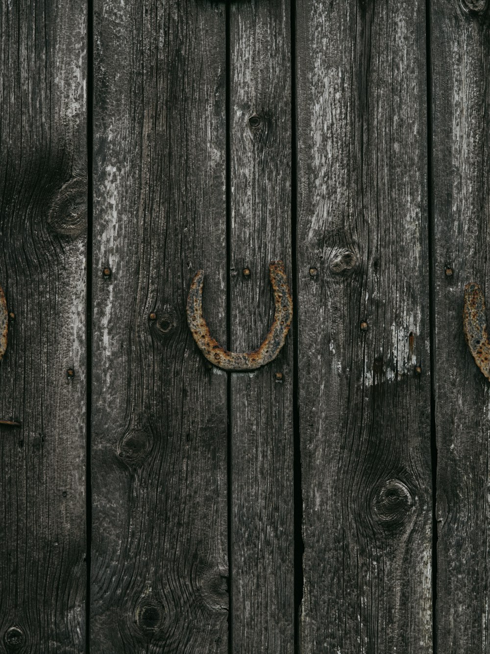 a close up of a wooden fence with two horseshoes