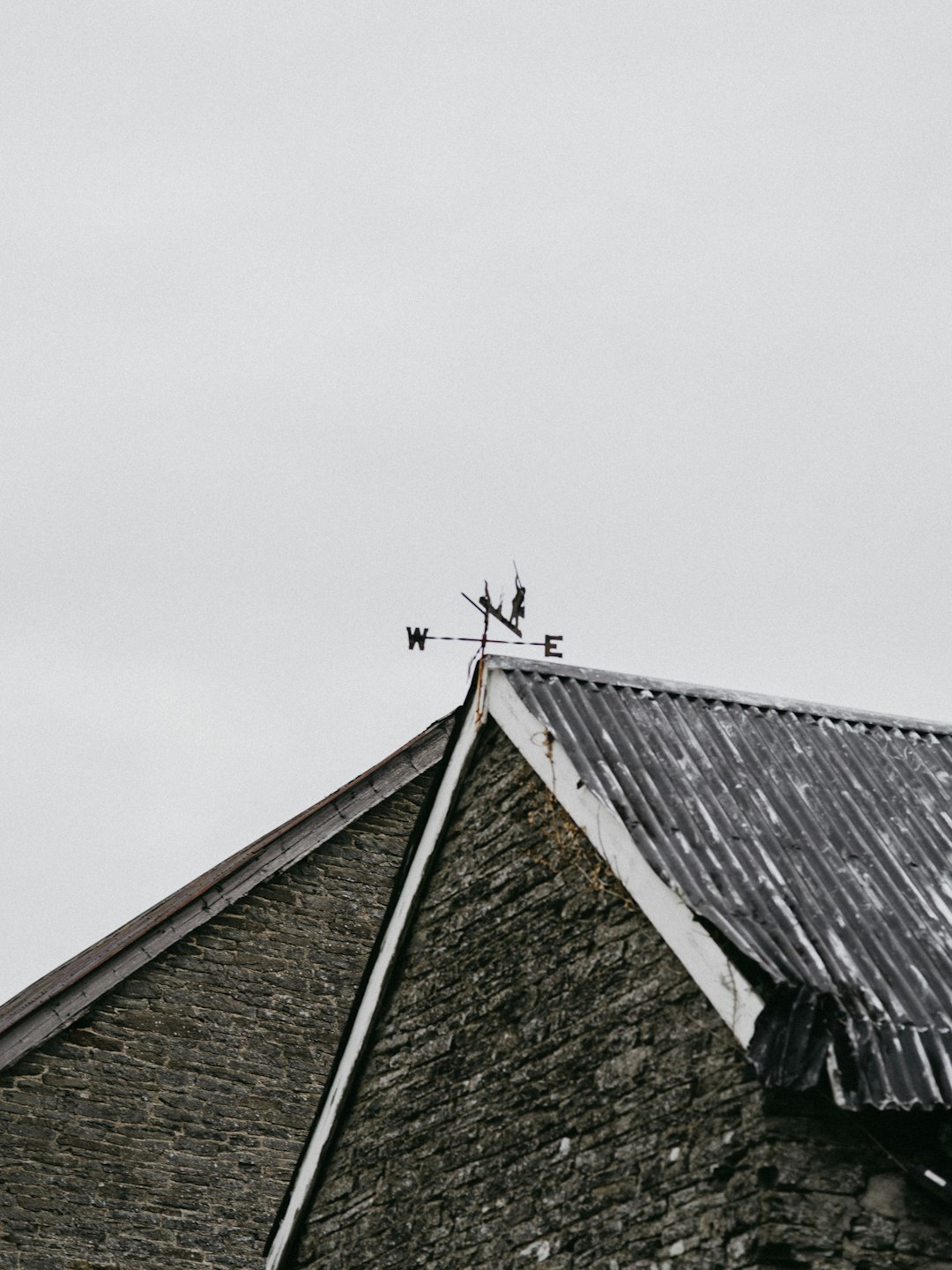 grayscale photography of wind vane on roof \