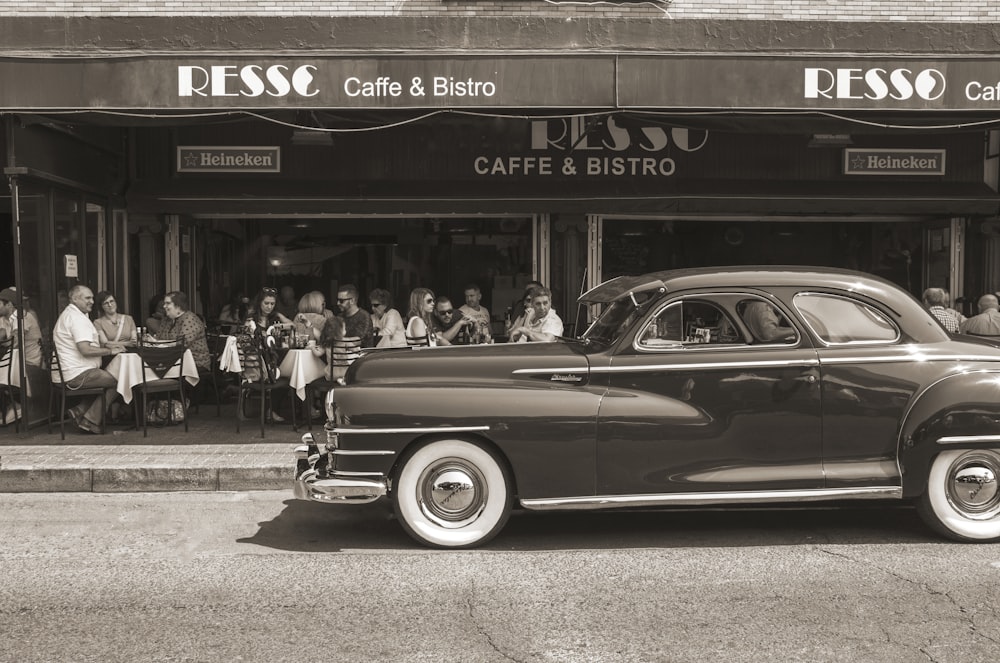 grayscale photo of vehicle park beside people