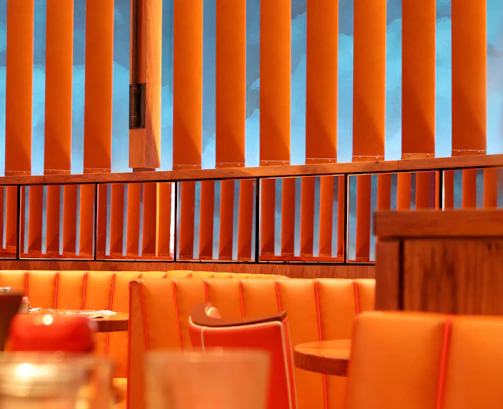 Warm, inviting shot of a Scandinavian-style restaurant corner with deep crimson accents and soft forest green details.