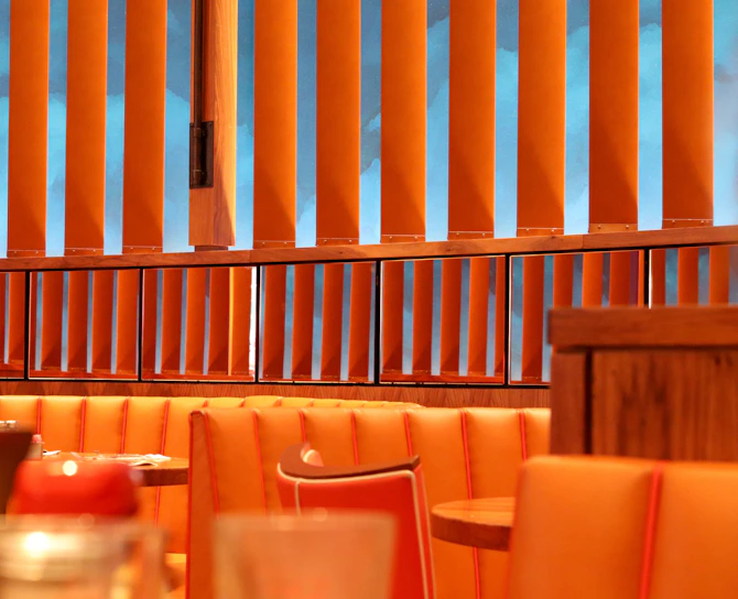 Warm-toned photo of a Scandinavian-style restaurant corner with matte forest green walls and deep crimson accents.