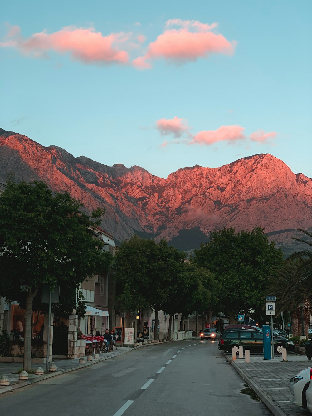 vehicles parked beside road near mountain during daytime