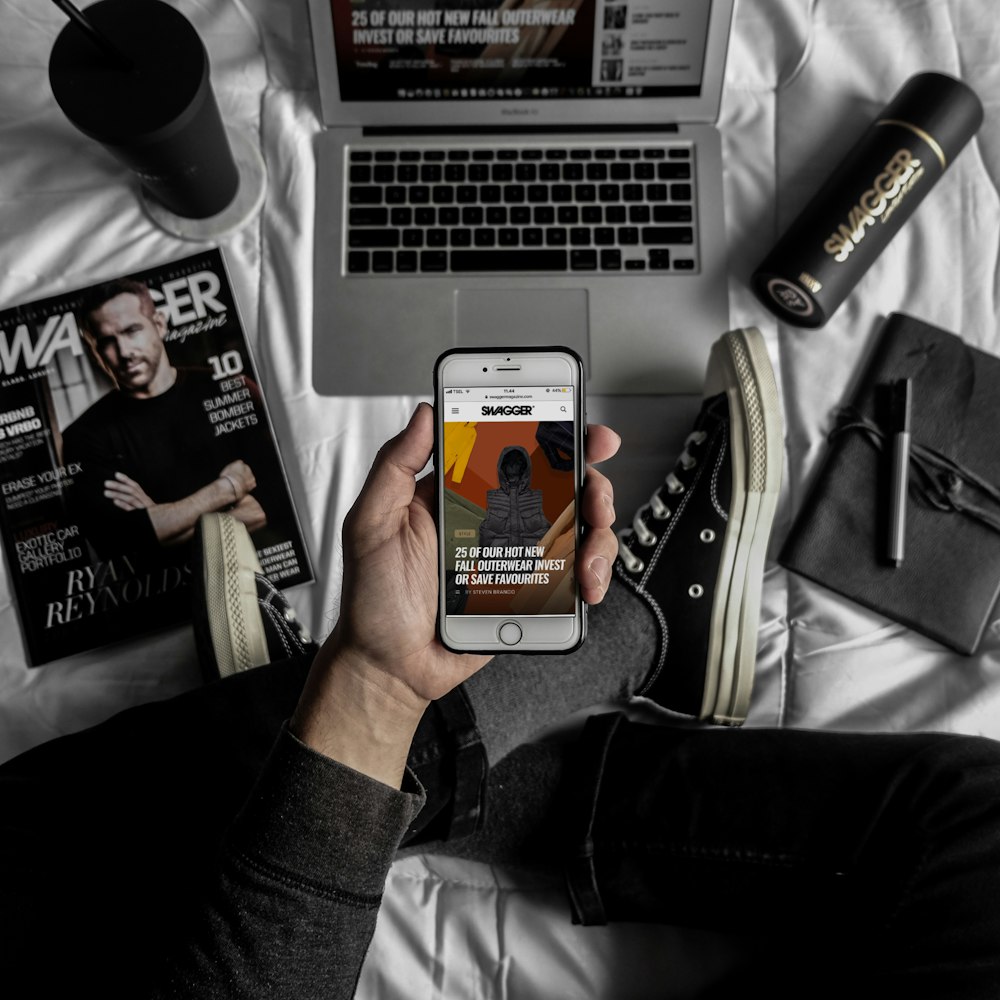 person holding silver iPhone 5s on bed