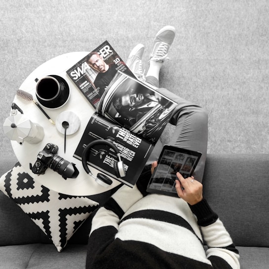 A foldable portable phone stand holding a tablet, placed on a cozy couch.