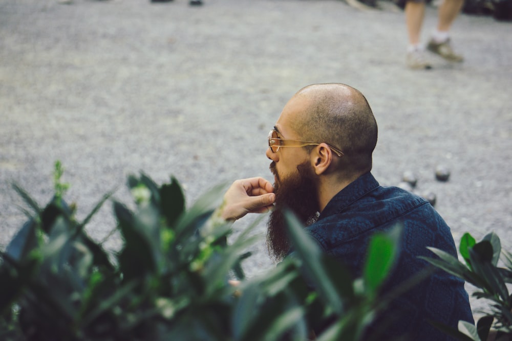 man in blue dress shirt sitting beside plants