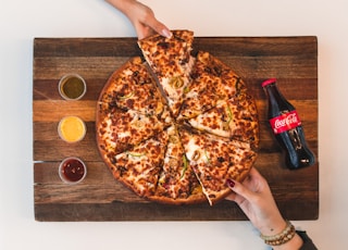 eight sliced pizza with Coca-Cola bottle beside