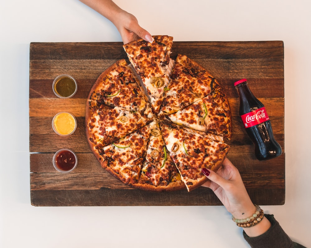 Pizza de ocho rebanadas con botella de Coca-Cola al lado