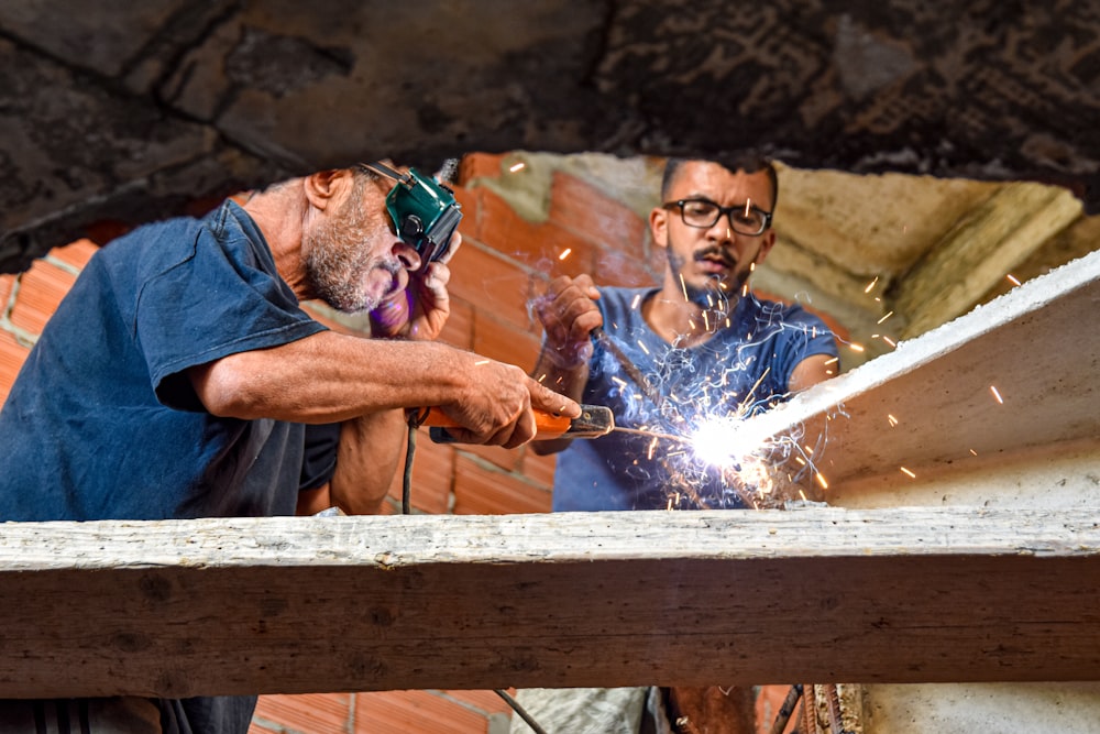 two men standing while welding