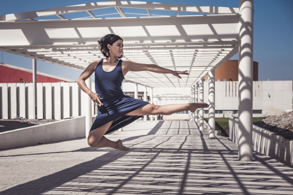 woman jumping wearing blue sleeveless dress during daytime