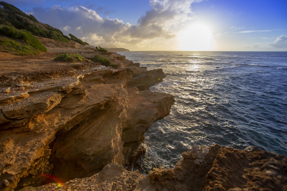 wavy body of water beside rock formation