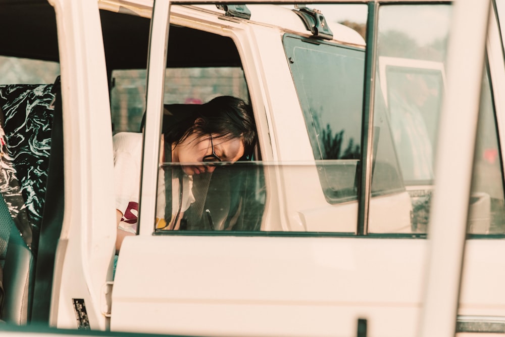 Foto de enfoque superficial de una persona en un coche blanco