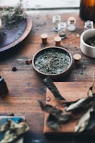 A rustic wooden table displaying jars of flavored olive oils with herbs and spices