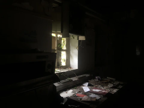 Close-up of an old NYC kitchen featuring faded cabinets and cluttered countertops under soft, yellowed light.