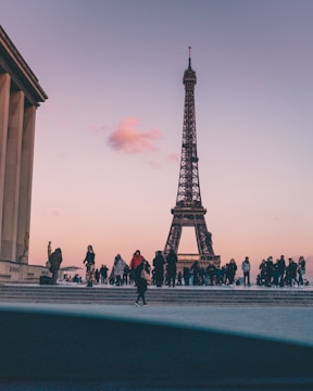 A lively group of travelers enjoying a guided tour in front of the Eiffel Tower at sunset.