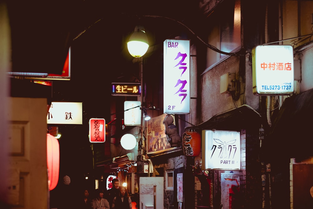 people walking near road beside buildings during night time