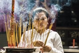 A serene moment of a woman meditating with incense smoke gently rising in the background.