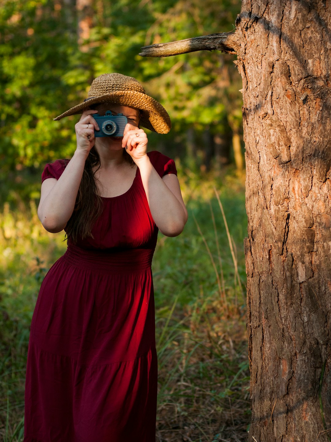 woman holding camera beside tree