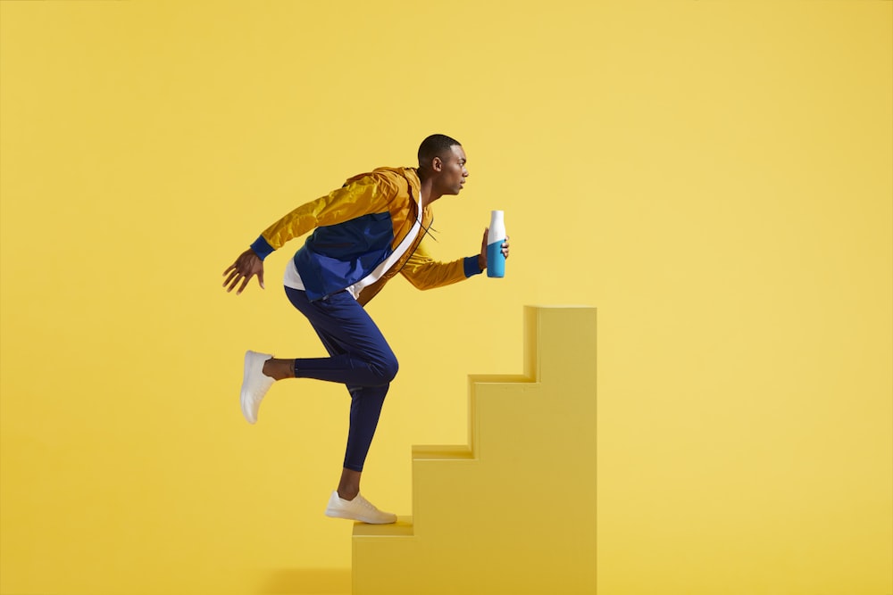 man in blue and yellow jacket and blue pants on yellow stair