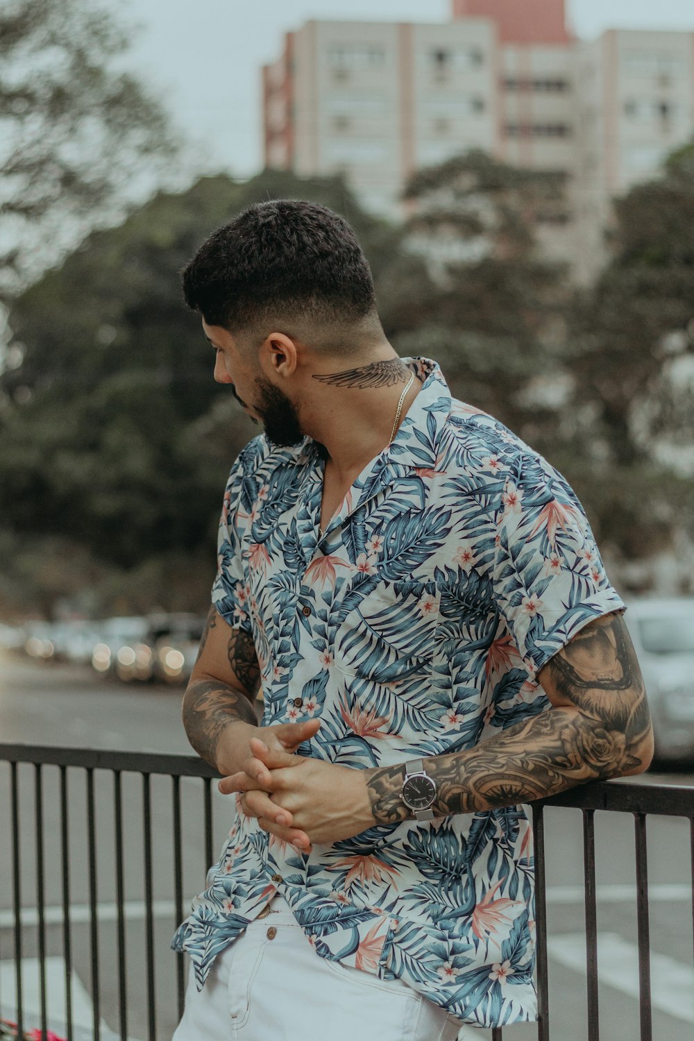 man in floral button-up shirt leaning on metal rail