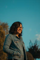 woman wearing blue denim jacket and eyeglasses standing and laughing