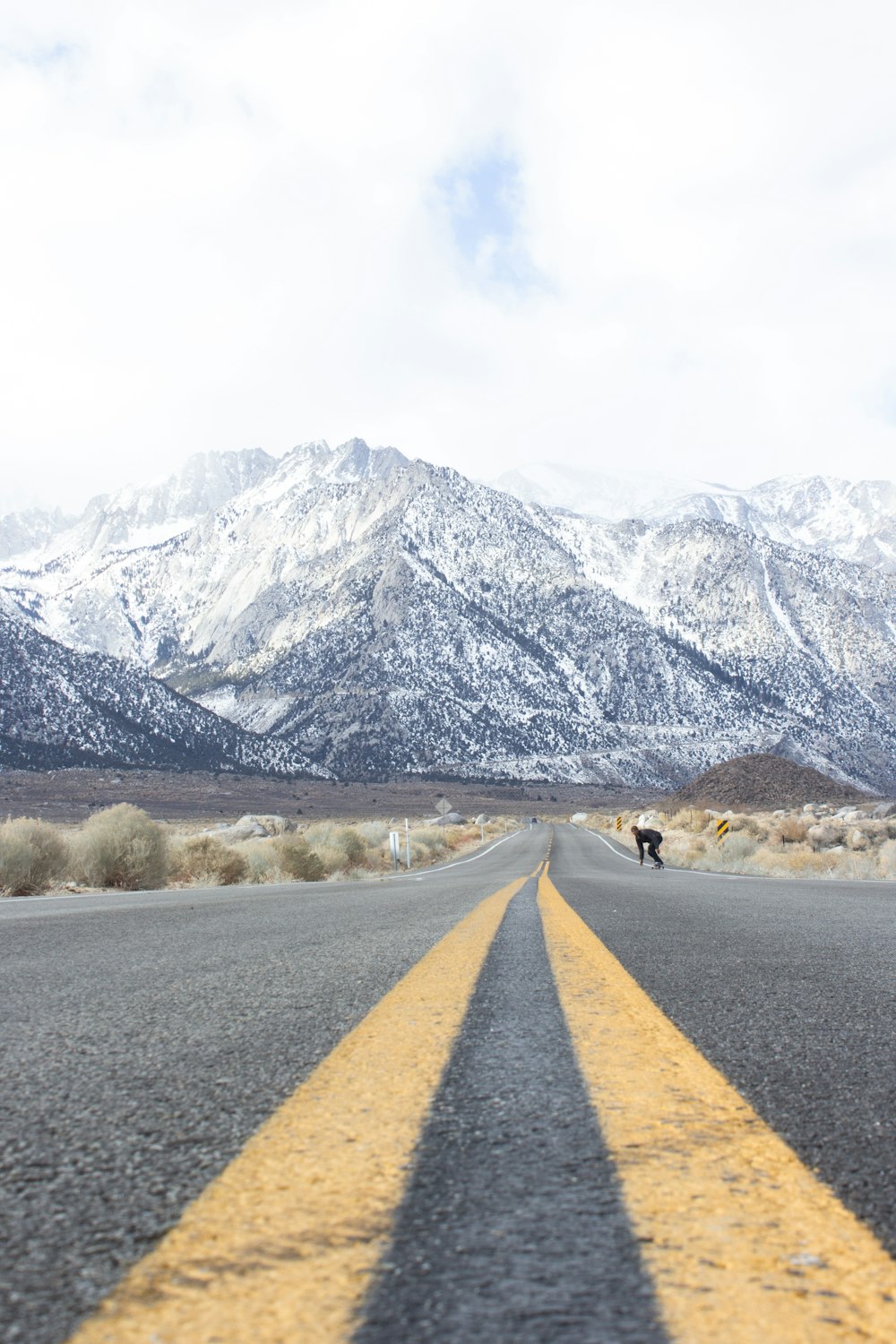 yellow and grey highway with view of snow-capped mountain