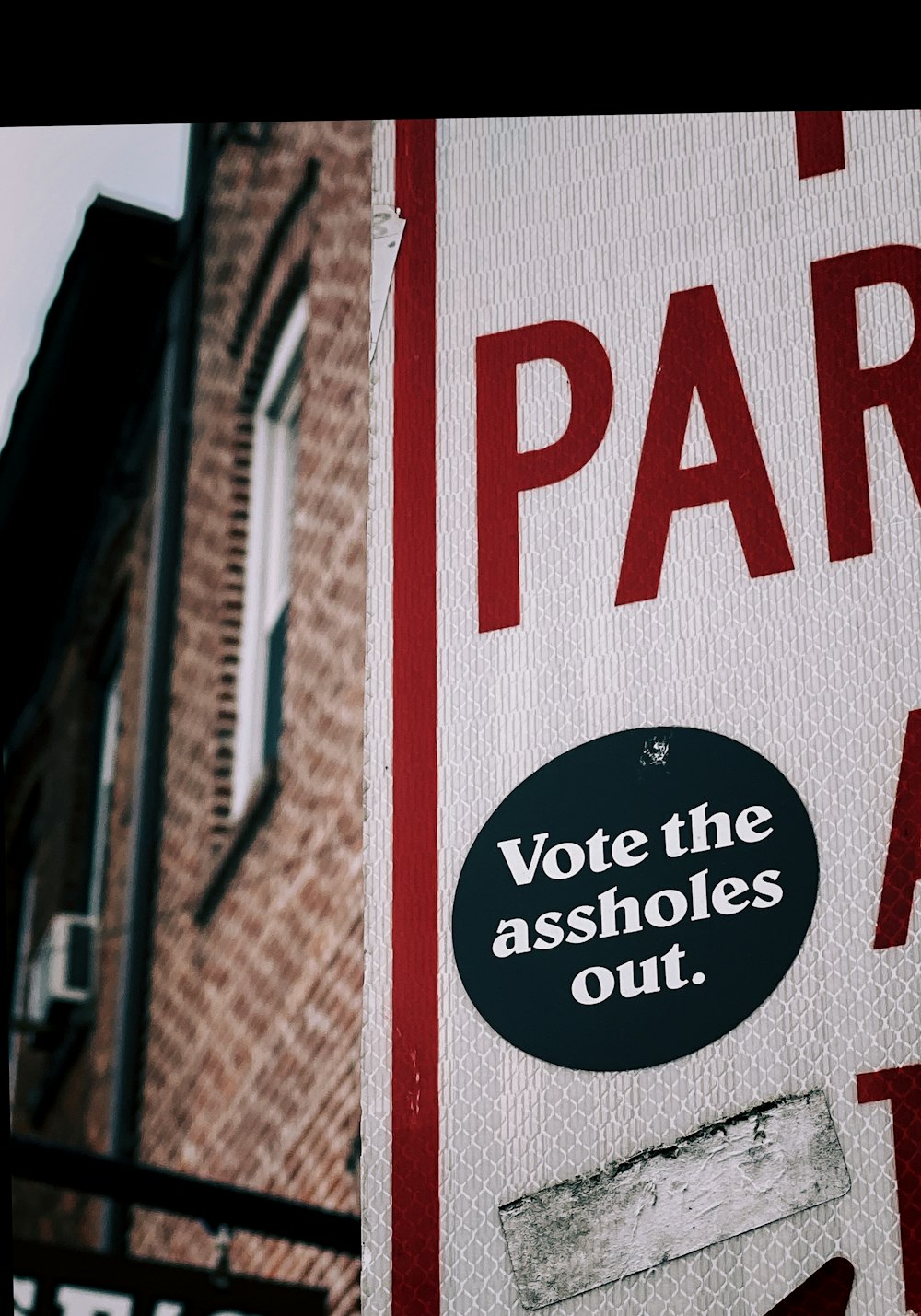 a red and white sign that says vote the assholes out