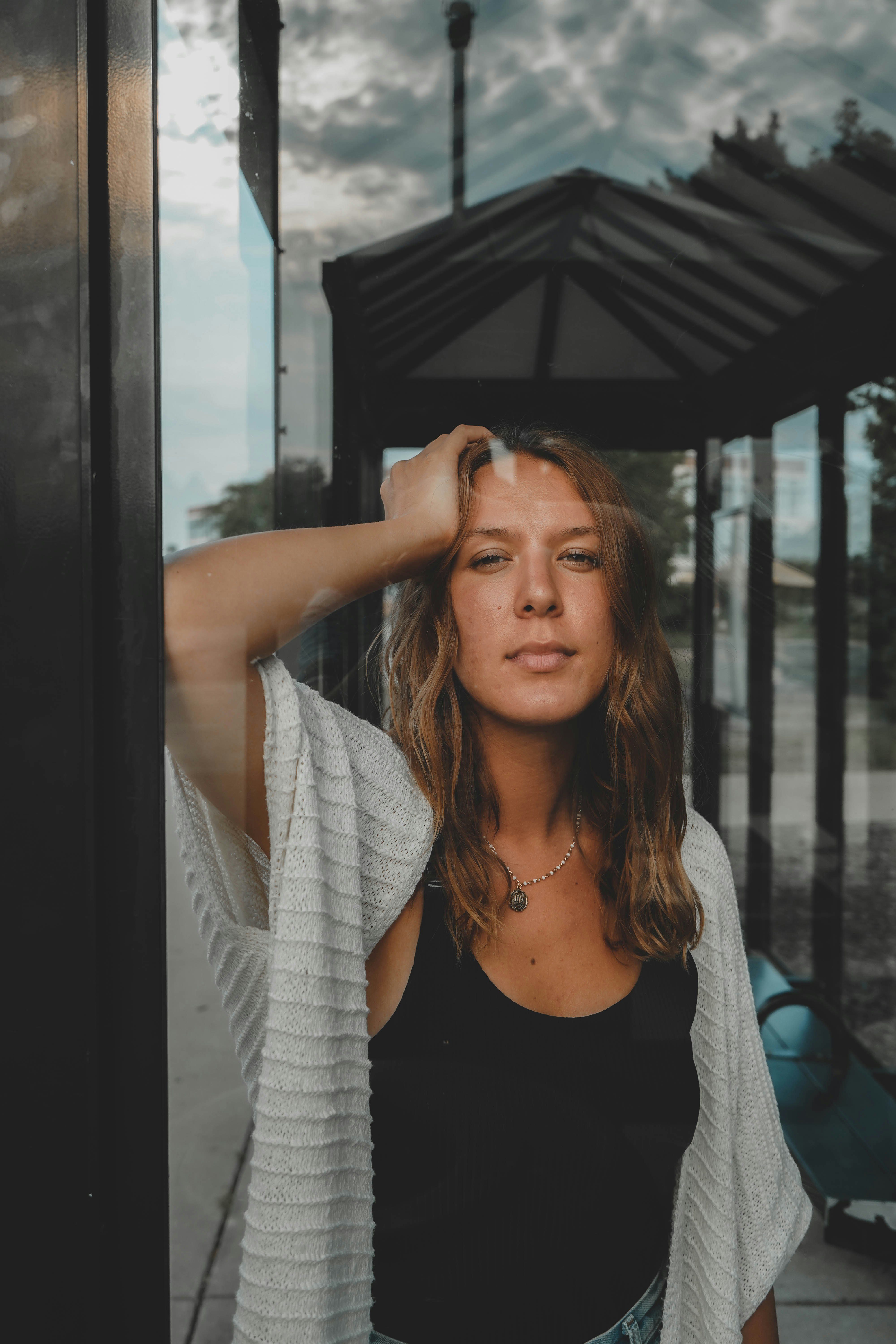 woman wearing white cardigan leaning on wall