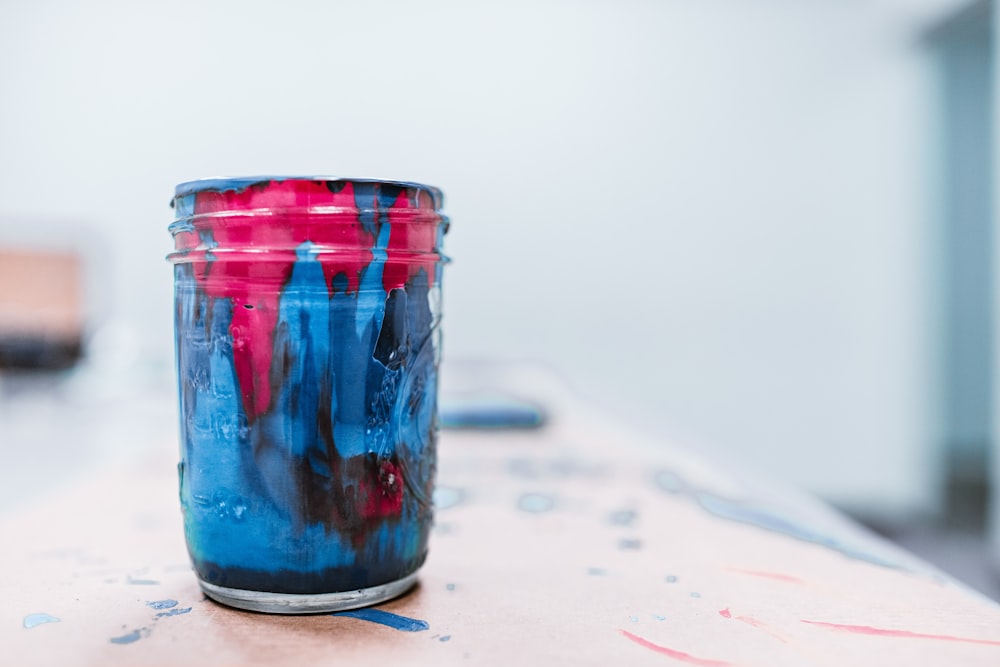 Tarro de pintura azul y rojo sobre surace blanco