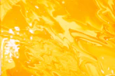 Swirling patterns of bright yellow and orange liquid paint