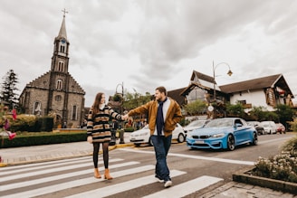 a man and woman crossing a street in front of a church