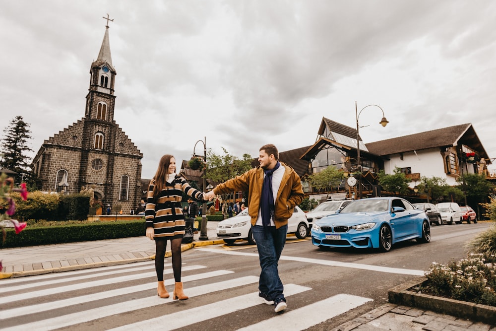 a man and woman crossing a street in front of a church