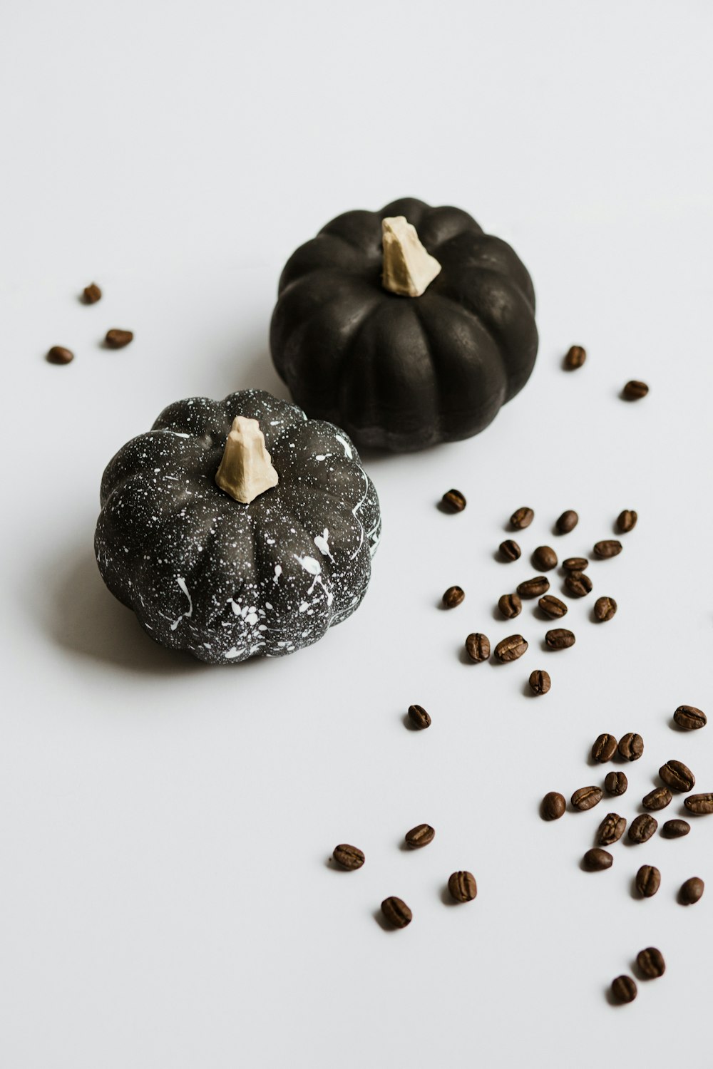 two black pumpkins on white surface