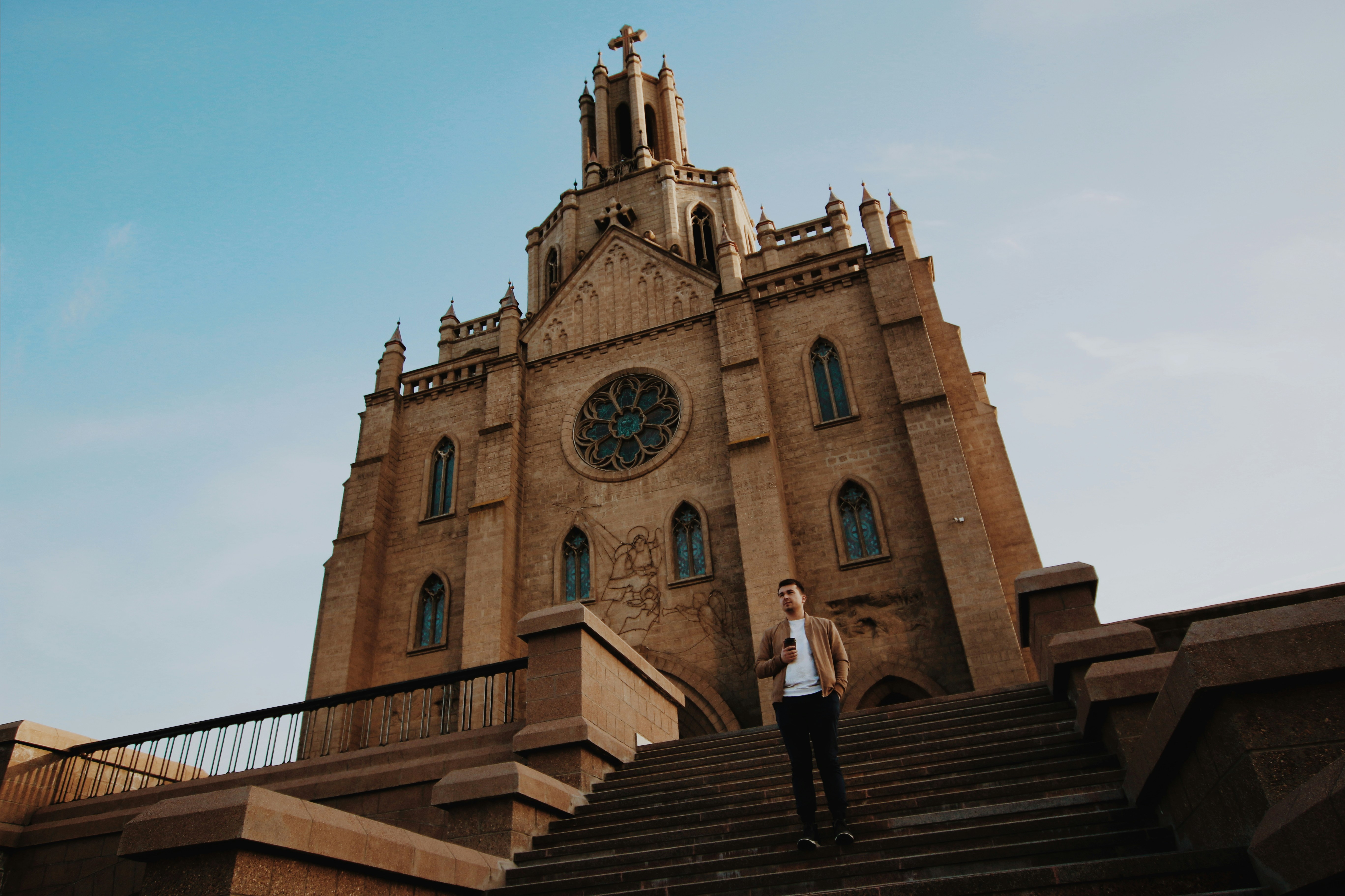man standing on stairs in front of church during day