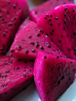 Slices of vibrant pink dragon fruit with black seeds scattered across the flesh, showcasing a rich and juicy texture.