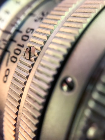 A close-up view of a metallic, textured dial with engraved numbers and lines, suggesting precision and craftsmanship. The image highlights the intricate details and machining of the object.