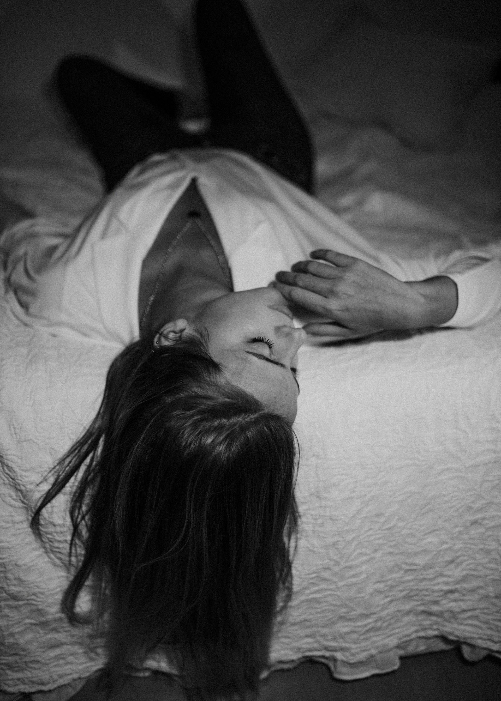 gray-scale photo of woman laying on bed