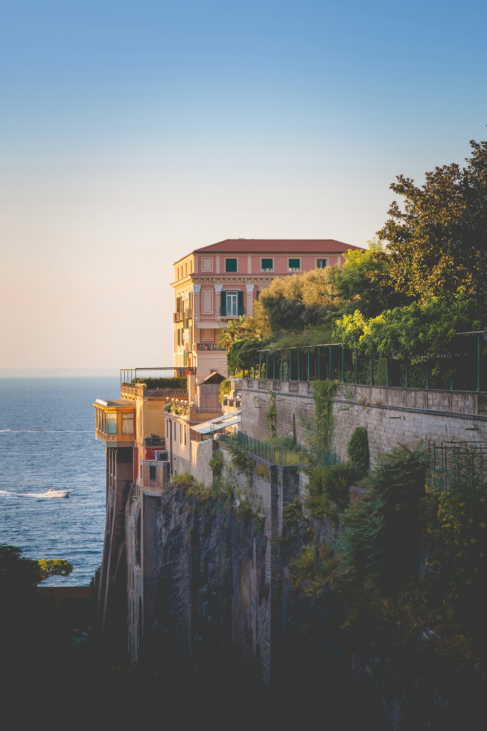 Maison en béton rose sur la falaise avec vue sur la mer bleue pendant la journée