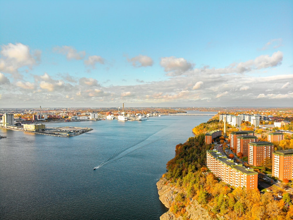 aerial photography of city with high-rise buildings viewing blue sea under white and blue sky during daytime