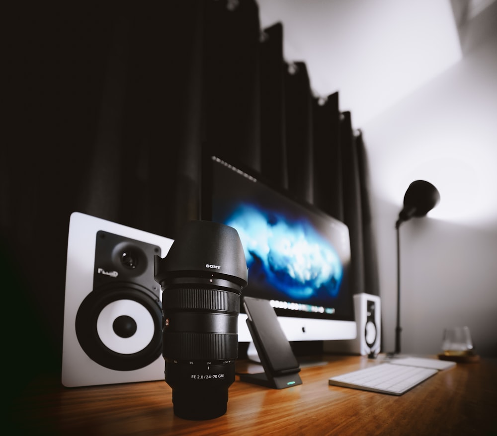 silver iMac near Apple Magic keyboard and black zoom lens on table