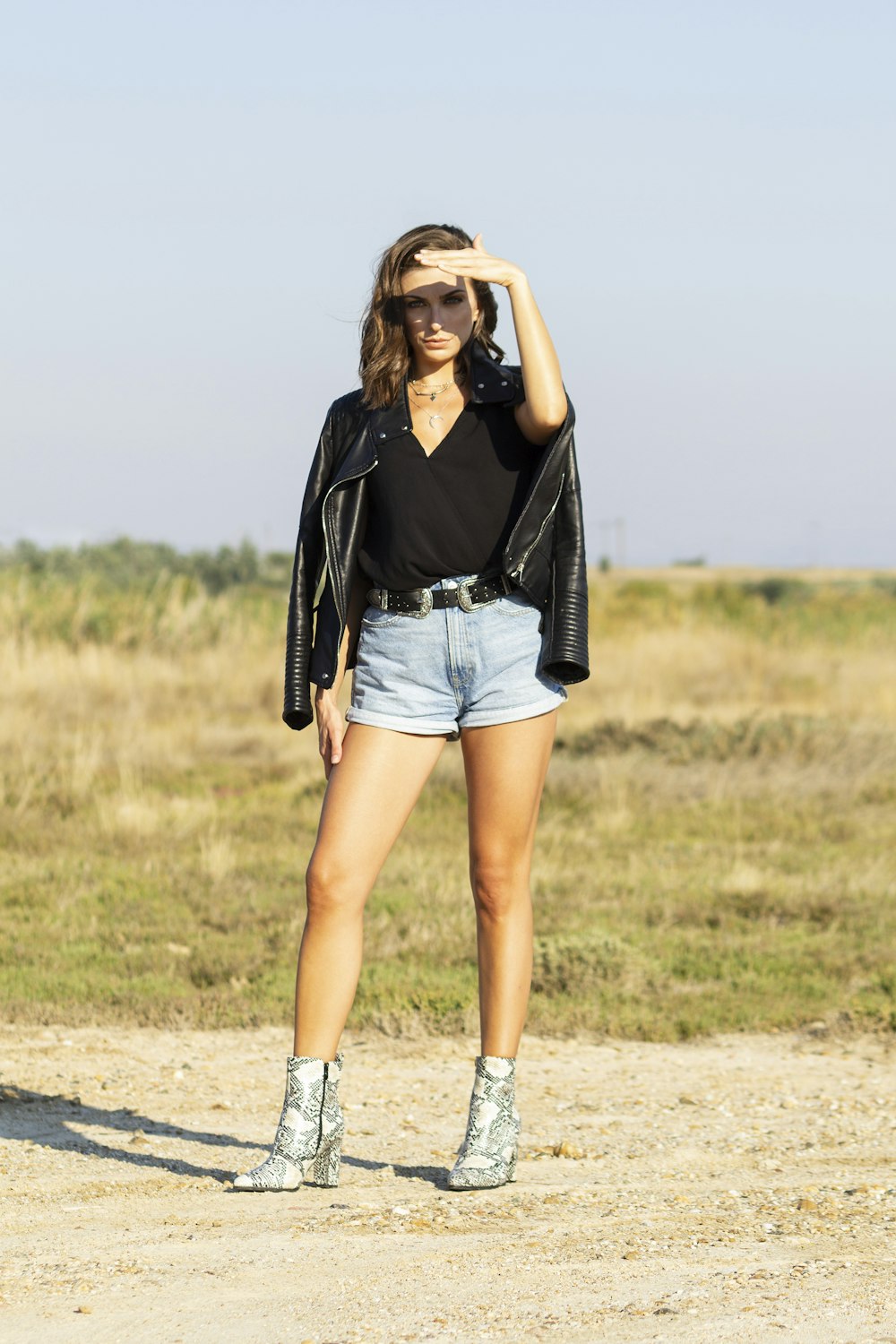 woman in white V-neck shirt, black jacket, blue denim short-shorts and silver leather booties