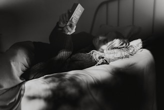 gray-scale photo of woman laying on bed
