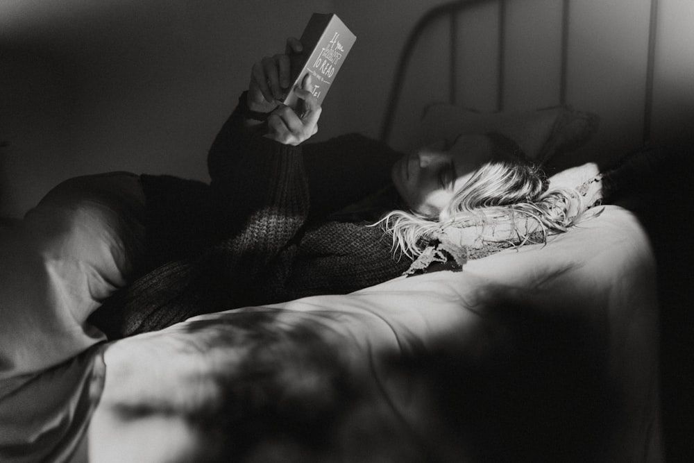 gray-scale photo of woman laying on bed