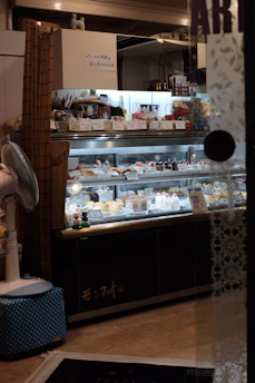A warm display case filled with colorful Italian pastries, glowing under soft bakery lighting.