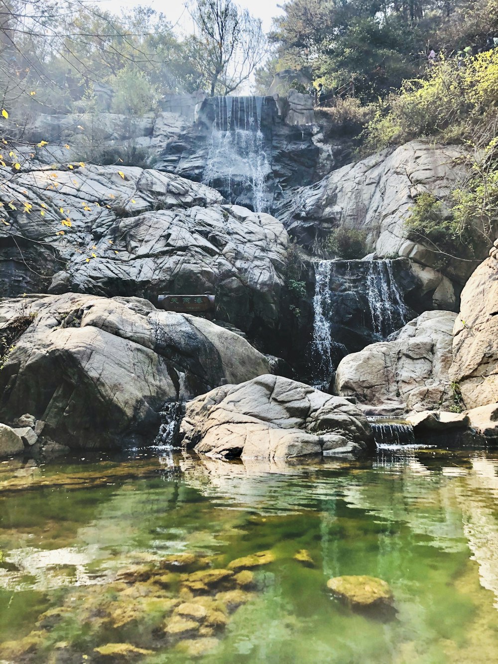 waterfalls on rock formation with calm body of water