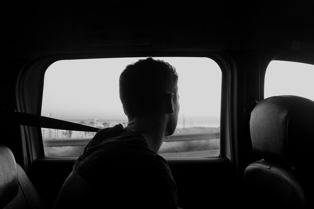 man sitting inside vehicle grayscale photo