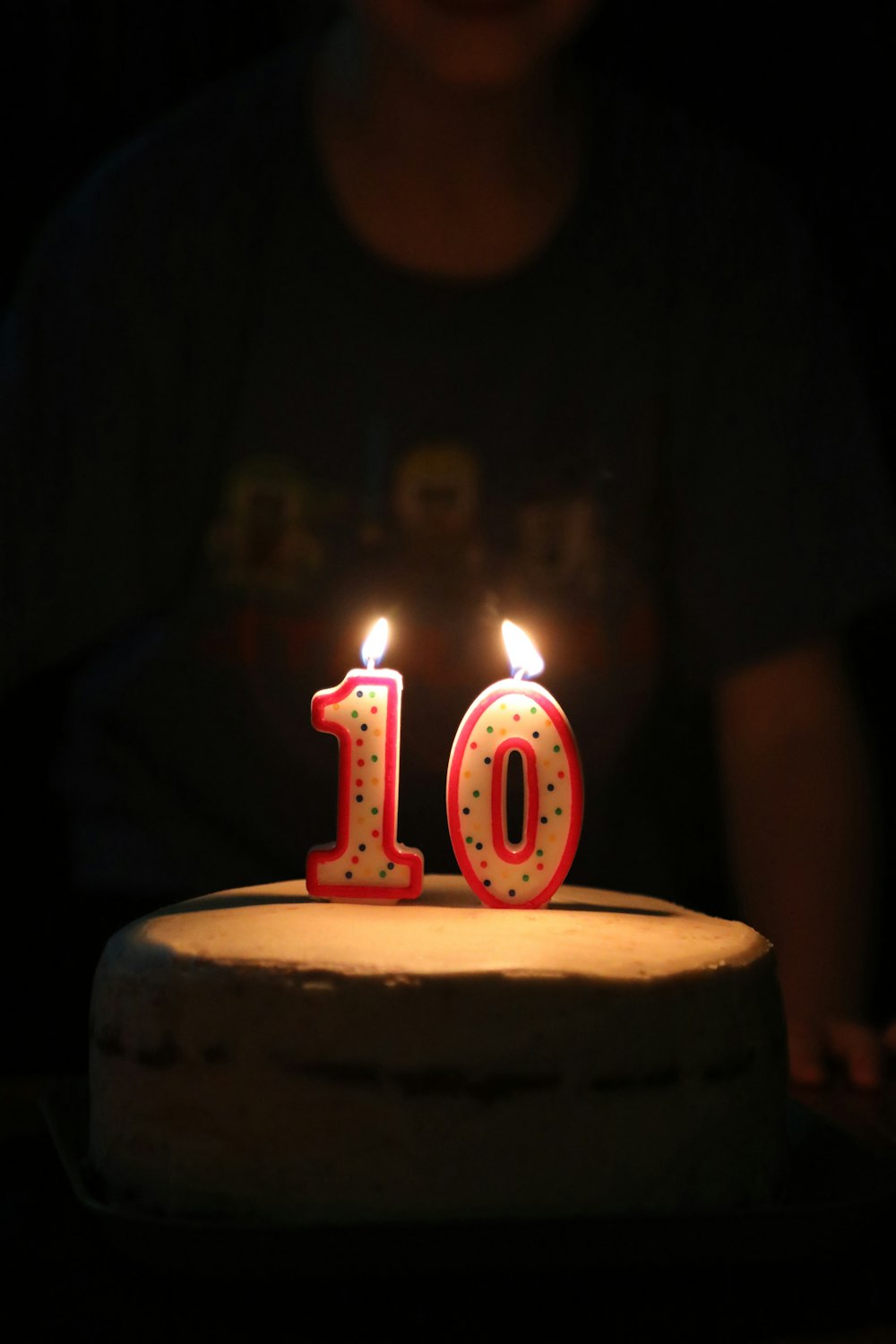 person standing beside cake with 10 candles