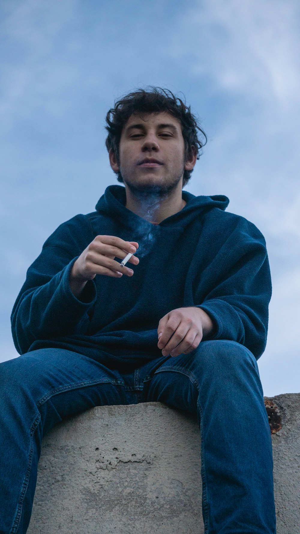 man in blue hoodie smoking