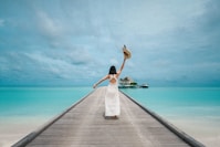 woman wearing white dress standing on sea dock