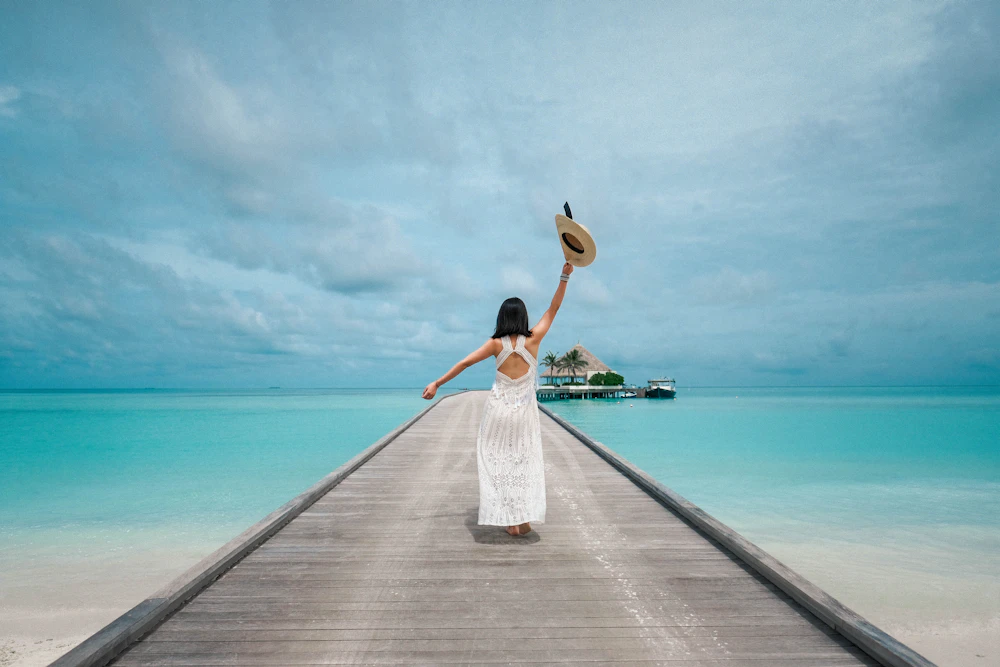 A woman smiling while enjoying a redeemed travel reward by the sea