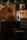 A vintage-style interior decorated with dark wooden furniture, an old radio, and a vintage fan. The walls have a rustic design with brickwork and antique light fixtures. Shelves hold various decorative vases and teapots, adding to the classic ambiance.